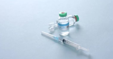 Ensülin tüplerini ve şırıngayı mavi arka planda fotokopi uzayıyla kapatın, yavaş çekim. Kan şekeri, Diyabet ve Sağlık Bilinci.