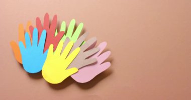 Kahverengi arkaplanda fotokopi alanı olan renkli kağıtlardan yapılmış elleri birbirine yakın tutun. Topluluk, küresel, insanlar ve sanat.