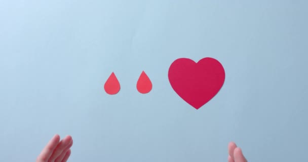白人的手捂住心脏血滴在蓝色的背景上慢动作献血 药物和保健 — 图库视频影像