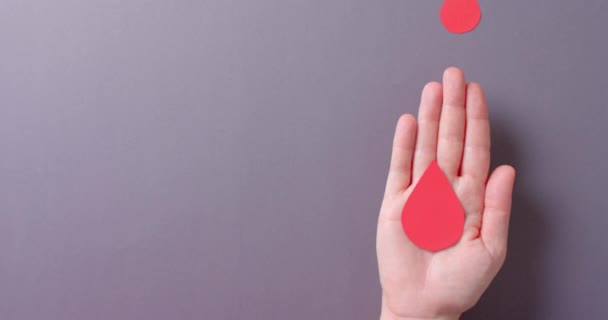 コピースペースで灰色の背景に血滴を保持している白人女性の手 スローモーション — ストック動画