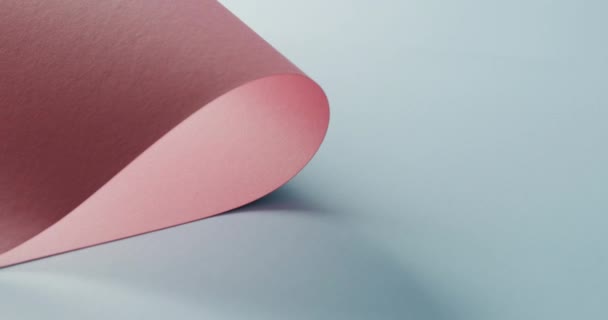 在淡蓝色背景上用慢动作的复制空间关闭粉红色滚动纸 材料和织物 — 图库视频影像