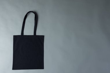 Gri arkaplanda kopya alanı olan siyah branda çantanın yüksek açılı görüntüsü. Çantalar ve moda konsepti.
