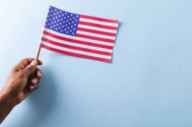 Amerika Birleşik Devletleri bayrağını elinde tutan melez bir adamın eli. Amerikan vatanseverliği, bağımsızlık günü ve gelenek kavramı.