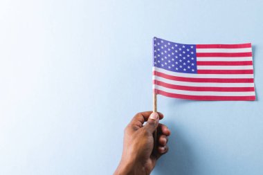 Amerika Birleşik Devletleri bayrağını elinde tutan melez bir adamın eli. Amerikan vatanseverliği, bağımsızlık günü ve gelenek kavramı.