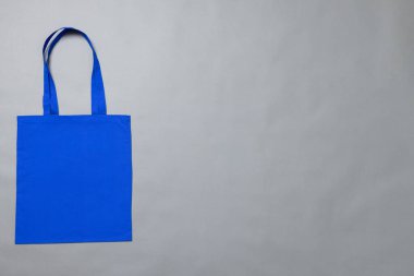 Üzerinde gri arkaplan bulunan mavi tuval çantasının yüksek açılı görüntüsü. Çantalar ve moda konsepti.