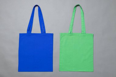 Gri arkaplanda kopya alanı olan mavi ve yeşil tuval çantaların yüksek açılı görüntüsü. Çantalar ve moda konsepti.