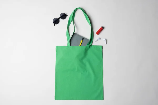 ノートブック サングラス イヤフォン ライター コピースペースと緑のキャンバスバッグの高い角度ビュー バッグとファッションのコンセプト — ストック写真