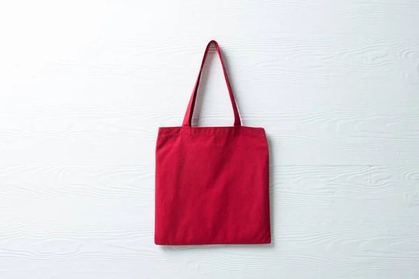 Close up of hanging red canvas bag with copy space on white background. Bags and fashion concept.