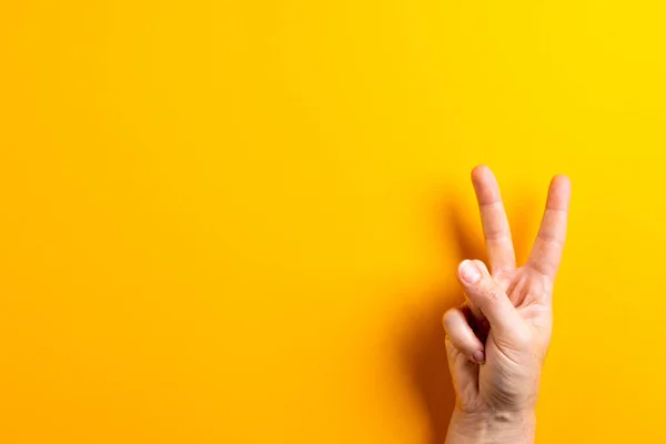 stock image Close up of hand of caucasian woman showing peace sign with copy space on yellow background. Peace and anti war movement concept.