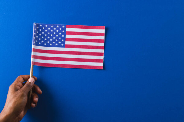 Hand of biracial man holding flag of united states of america with copy space. American patriotism, independence day and tradition concept.