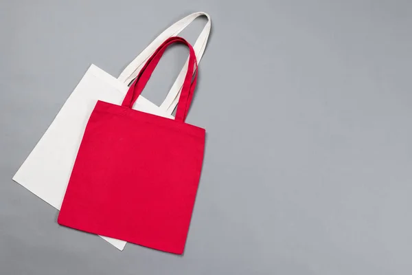 Close up of white and red canvas bags with copy space on grey background. Bags and fashion concept.
