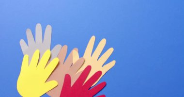 Mavi arkaplanda fotokopi alanı olan renkli kağıtlardan yapılmış elleri birleştirin. Topluluk, küresel, insanlar ve sanat.