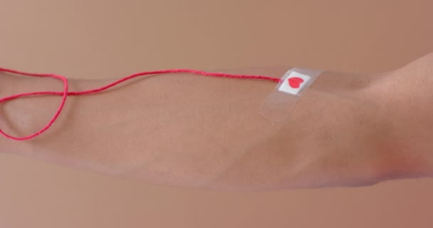 手长有血滴 红线和红心贴在米黄色上的红心石膏 动作缓慢 药物和保健 — 图库视频影像