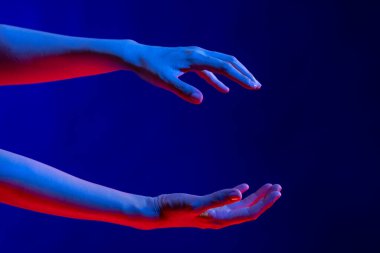 Asyalı kadın stüdyoda elleri ve mavi ışığı ile fotokopi çekerek jestler yapıyor. Sanal gerçeklik ve dijital arayüz teknolojisi.