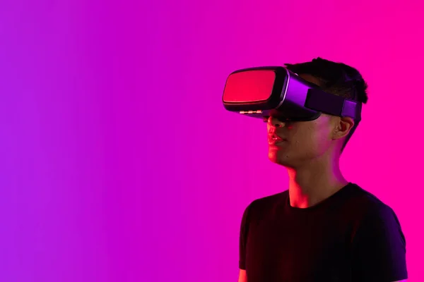 紫色の光とコピースペースのスタジオでVrヘッドセットを使用してアジアの男 仮想現実とデジタルインターフェース技術 — ストック写真