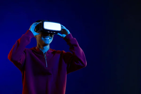 コピースペースのある青い光のスタジオでVrヘッドセットを保持する幸せなアジア人男性 仮想現実とデジタルインターフェース技術 — ストック写真