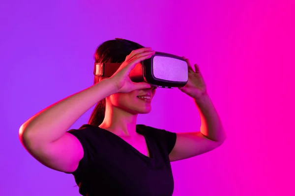 青とピンクの光とコピースペースのスタジオでVrヘッドセットを使用して幸せなアジアの女性 仮想現実とデジタルインターフェース技術 — ストック写真