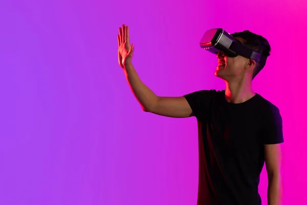 コピースペースのある紫色の光のスタジオでVrヘッドセットを使用して幸せなアジアの男 仮想現実とデジタルインターフェース技術 — ストック写真