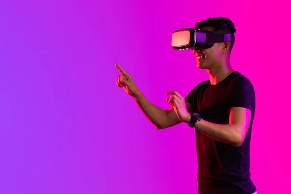 紫の光とコピースペースのスタジオでVrヘッドセットを使用して幸せなアジアの男 仮想現実とデジタルインターフェース技術 — ストック写真