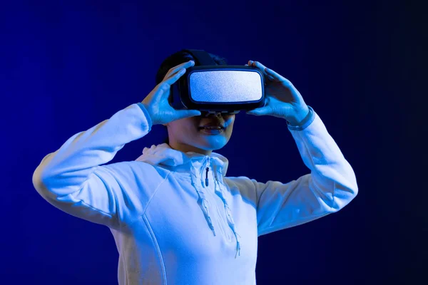 スタジオで青い光でVrヘッドセットを保持しているアジアの女性 仮想現実とデジタルインターフェース技術 — ストック写真
