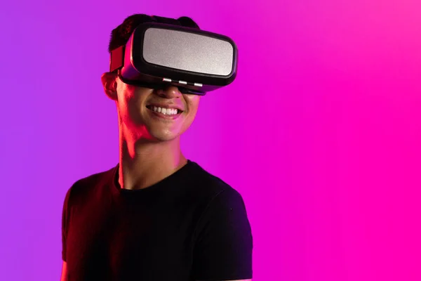 コピースペースのある紫色の光のスタジオでVrヘッドセットを使用して幸せなアジアの男 仮想現実とデジタルインターフェース技術 — ストック写真