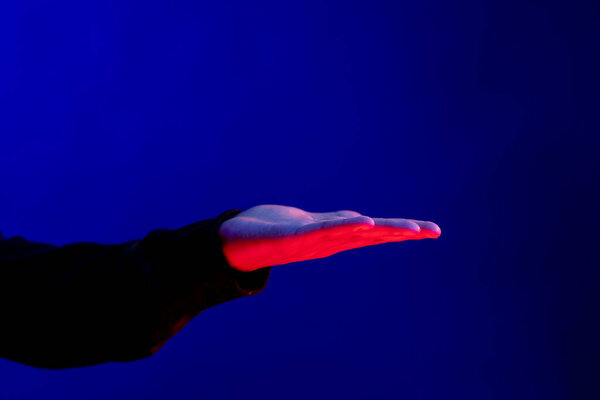 Asian man exposing hand in studio with blue light with copy space. Virtual reality and digital interface technology.