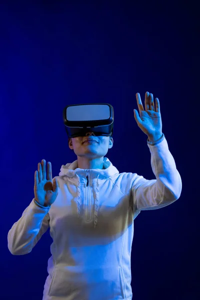 コピースペースのある青い光のスタジオでVrヘッドセットを使用するアジアの女性 仮想現実とデジタルインターフェース技術 — ストック写真