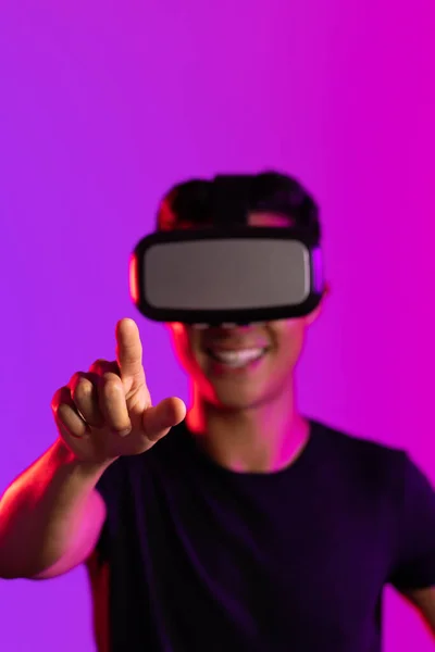 紫色の光のスタジオで指を指してVrヘッドセットを使用して幸せなアジアの男の肖像画 仮想現実とデジタルインターフェース技術 — ストック写真