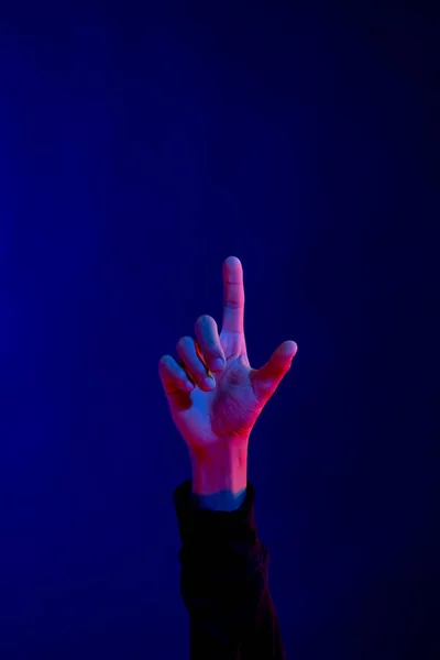 Asian man pointing finger in studio with blue light with copy space. Virtual reality and digital interface technology.