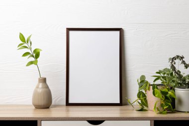 Fotokopi alanı olan siyah boş çerçeve ve beyaz duvarın karşısında saksıda bitkiler. Çerçeve şablonu, iç tasarım ve dekorasyonu düzenle.