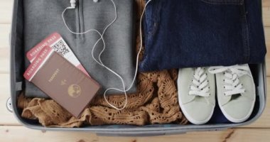 Pasaportlu bavulu kapat ve ahşap arka planda giysileri topla. Seyahat ve tatil kavramı.