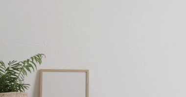 Beyaz zemin üzerinde kopya alanı olan ahşap çerçeve ve masa üzerinde beyaz duvarla birlikte bitki. Çerçeve, ev dekorasyonu ve iç tasarım konsepti.