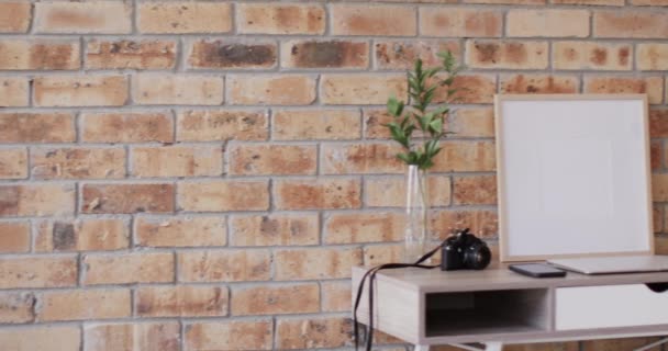 レンガの壁に対して机の上に植物と白い背景にコピースペースと木製のフレーム フレーム 家の装飾とインテリアデザインのコンセプト — ストック動画