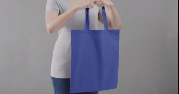 Blanke Vrouw Draagt Wit Shirt Met Blauwe Tas Grijze Achtergrond — Stockvideo