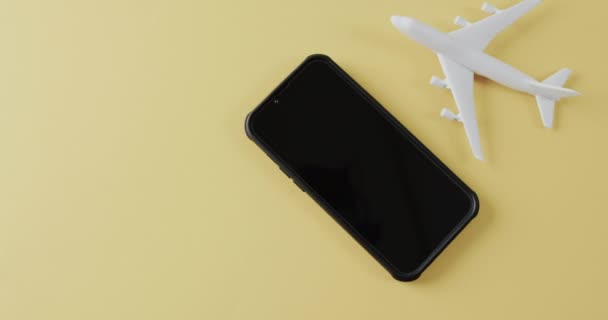 黄色の背景に白い平面モデル スマートフォンやコピースペースの閉鎖 航空旅行 休暇の概念 — ストック動画