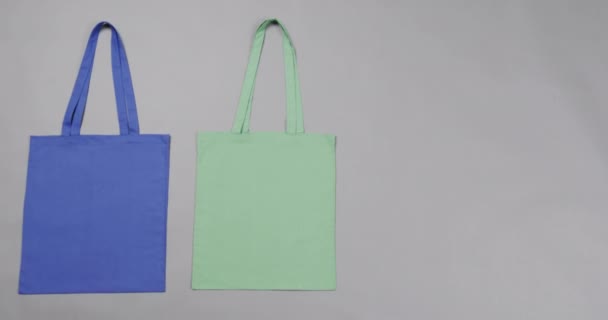 Großaufnahme Blauer Und Grüner Tüten Auf Grauem Hintergrund Mit Kopierraum — Stockvideo