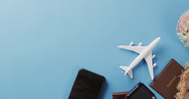 青の背景に白い平面モデル スマートフォンやコピースペースのクローズアップ 航空旅行 休暇の概念 — ストック動画