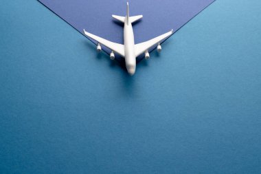 Mavi arka plandaki beyaz uçak modelini fotokopi alanı ile kapatın. Seyahat, ulaşım ve tatil.