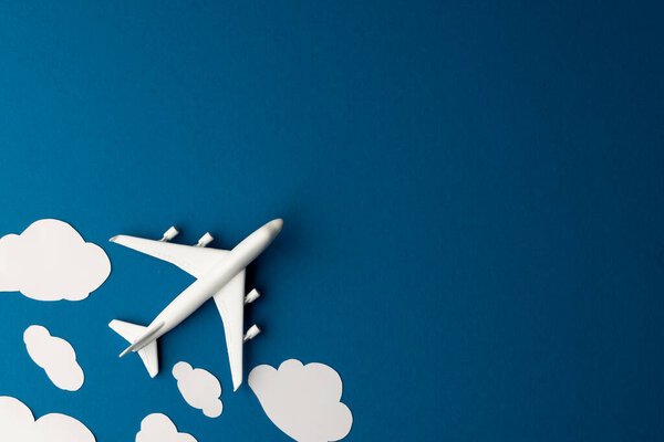 Close up of airplane model with clouds on blue background with copy space. Travel, transport and vacation.