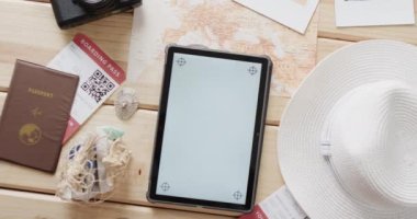 Tahta arka planda fotokopi alanı, pasaport ve güneş şapkası olan düz tablet. Seyahat ve tatil kavramı.