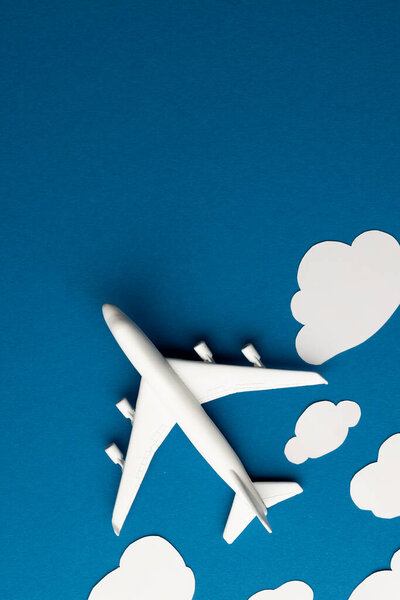 Close up of airplane model with clouds on blue background with copy space. Travel, transport and vacation.