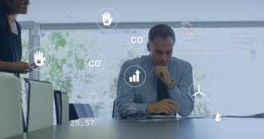 Ofisteki çeşitli iş adamları üzerinde ekolojik ikonlar ve veri işleme animasyonları. Küresel iş, finans, hesaplama ve veri işleme kavramı dijital olarak oluşturulmuş video.