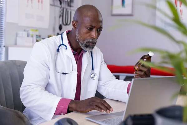 Afroamerikansk Manlig Läkare Som Sitter Vid Skrivbordet Och Håller Medicin — Stockfoto