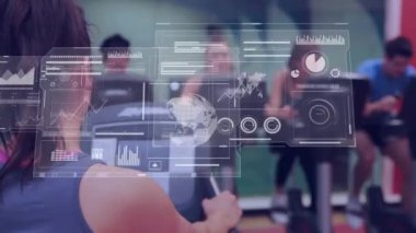 Kafkas kadın eğitmen ve sabit bisiklet kullanan insanların veri işleme animasyonları. Küresel spor, bilgisayar ve veri işleme kavramı dijital olarak oluşturulmuş video.