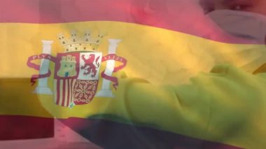 Yüz maskeli çift ırklı erkek cerrah yerine İspanya bayrağı animasyonu. Küresel tıp ve vatanseverlik, dijital olarak üretilen video.