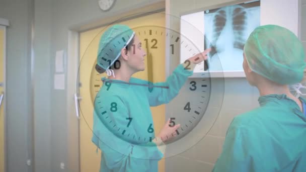 病院でX線レポートについて議論する2人の多様な女性外科医の上に時計をカチカチアニメーション 医療技術の概念 — ストック動画