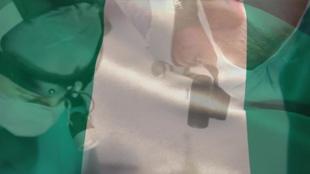 Animación Ondear Bandera Nigeria Contra Diversos Cirujanos Masculinos Femeninos Realizando — Vídeo de stock