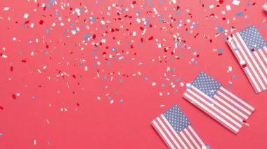 Kırmızı arka planda Amerika Birleşik Devletleri bayraklarının üzerine düşen konfeti animasyonu. Amerikan bağımsızlığı, gelenek ve kutlama konsepti dijital olarak oluşturulmuş video.