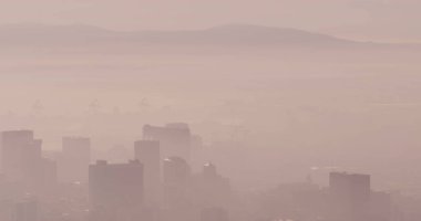 Genel olarak sisli şehir manzarası ve dağların üzerindeki modern binalar. Küresel iş ve şehir.