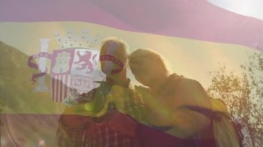 Dağlardaki Kafkasyalı yaşlı çiftin üzerinde İspanya bayrağı animajı. Seyahat ve vatanseverlik kavramı, dijital olarak üretilen video..